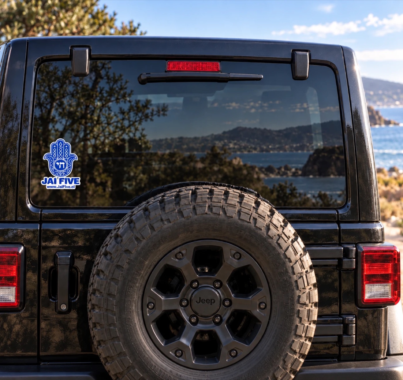 Sticker Jai Five pegado en el vidrio trasero de un jeep negro, con el mar de fondo
